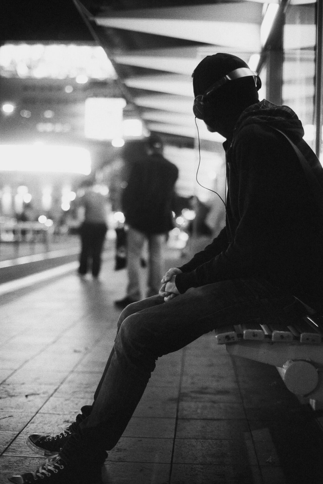 Person sitting on a bench in a city listening to music through headphones
