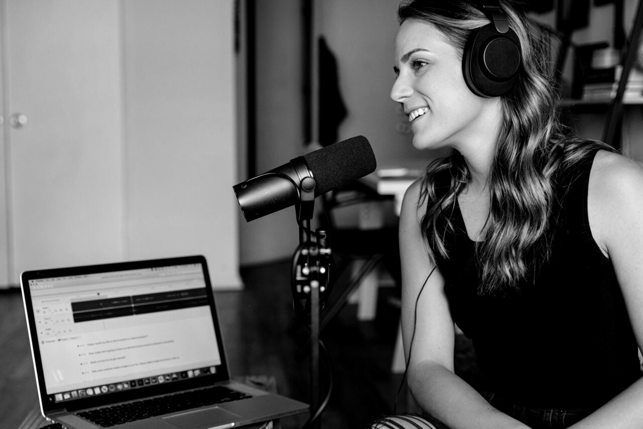 Presenter wearing headphones speaking into a studio microphone