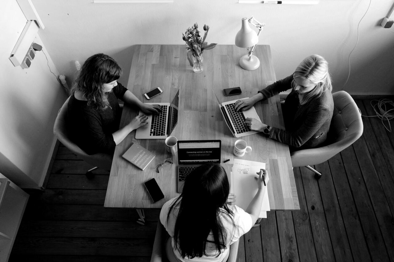 Overhead view of a team planning around a table covered in laptops