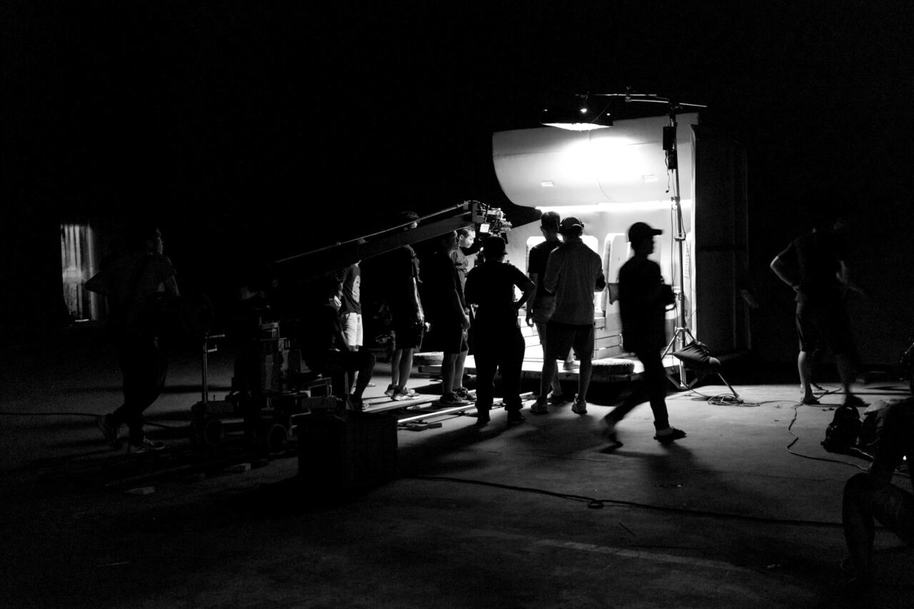 Video production crew around a camera on a darkened set